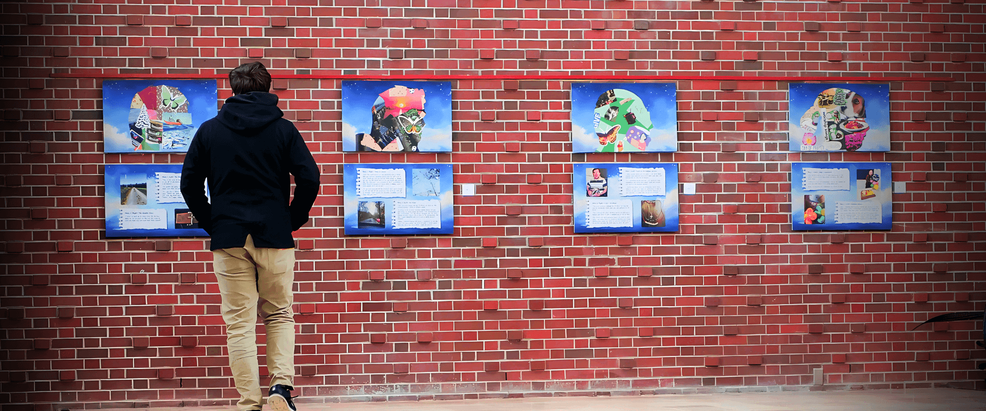 A visitor views the Images of God exhibit panels on the brick wall at Martin Luther University College.
